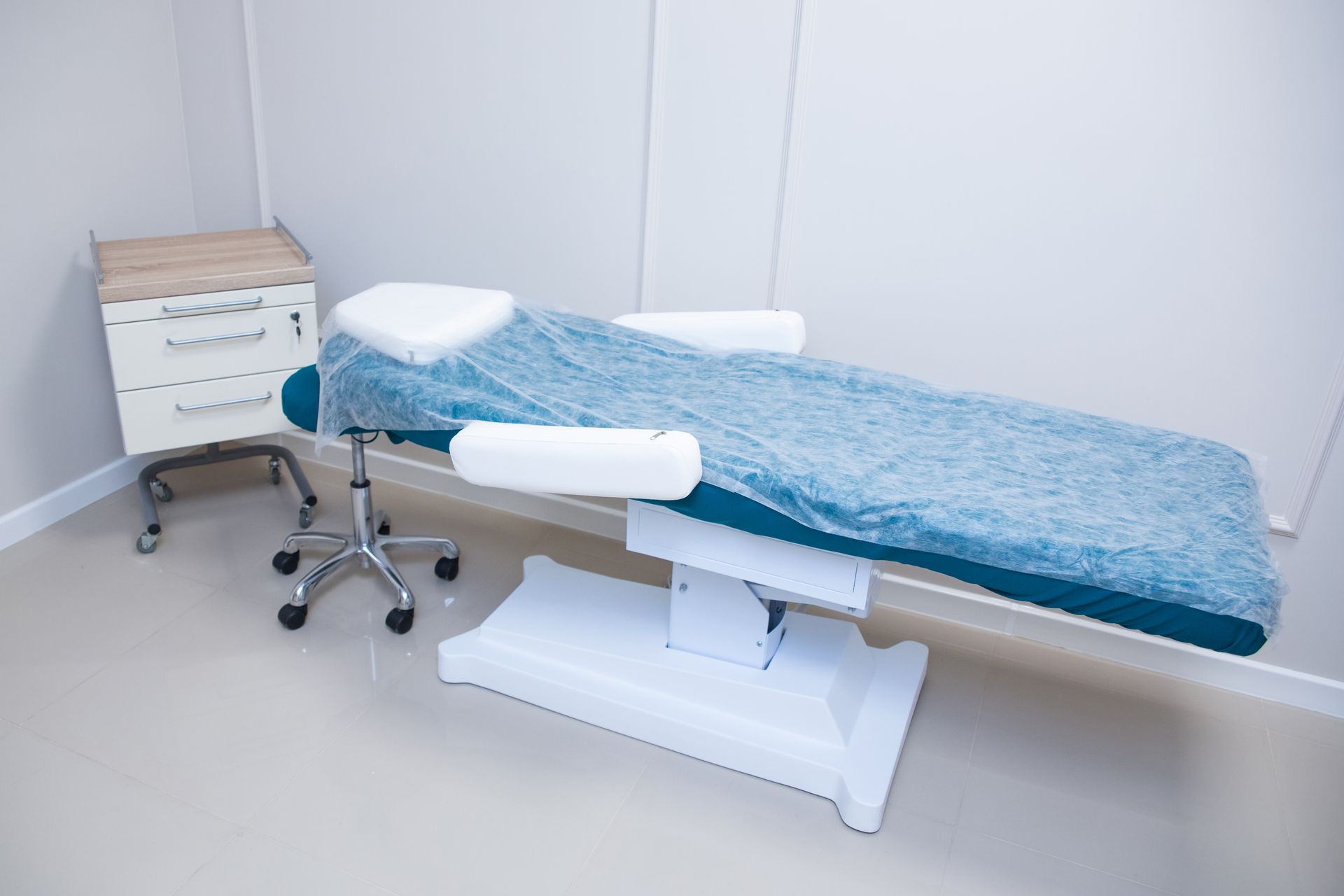 Clean medical examination room with treatment table and clinical equipment
