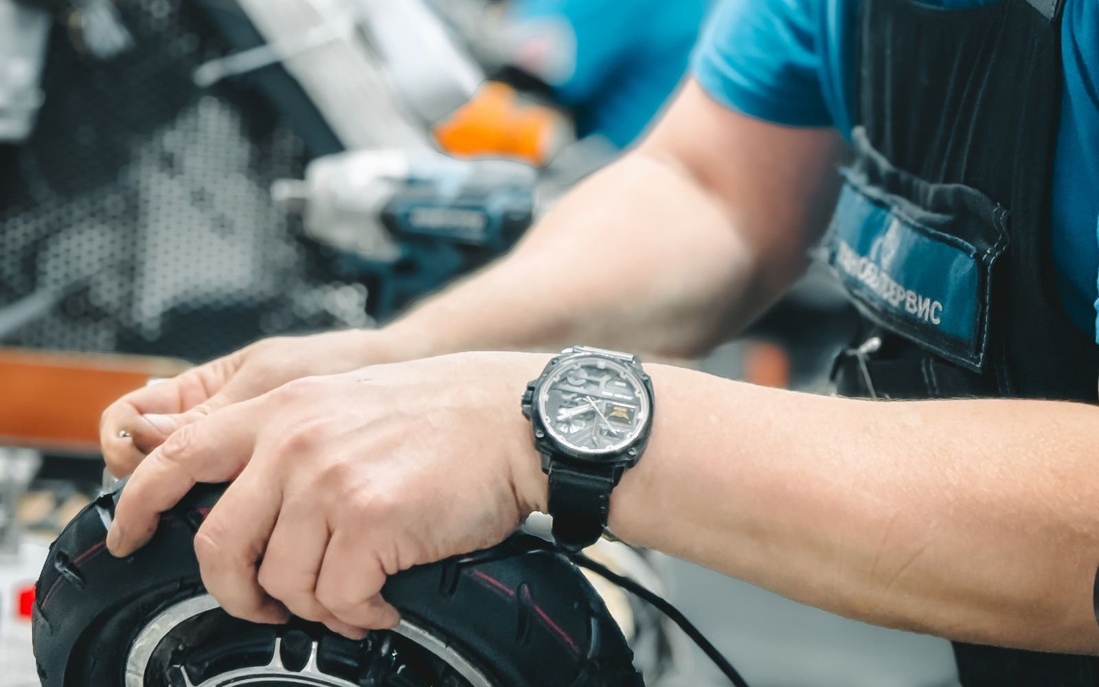 Technician repairing a mobility scooter wheel and motor on a workshop bench